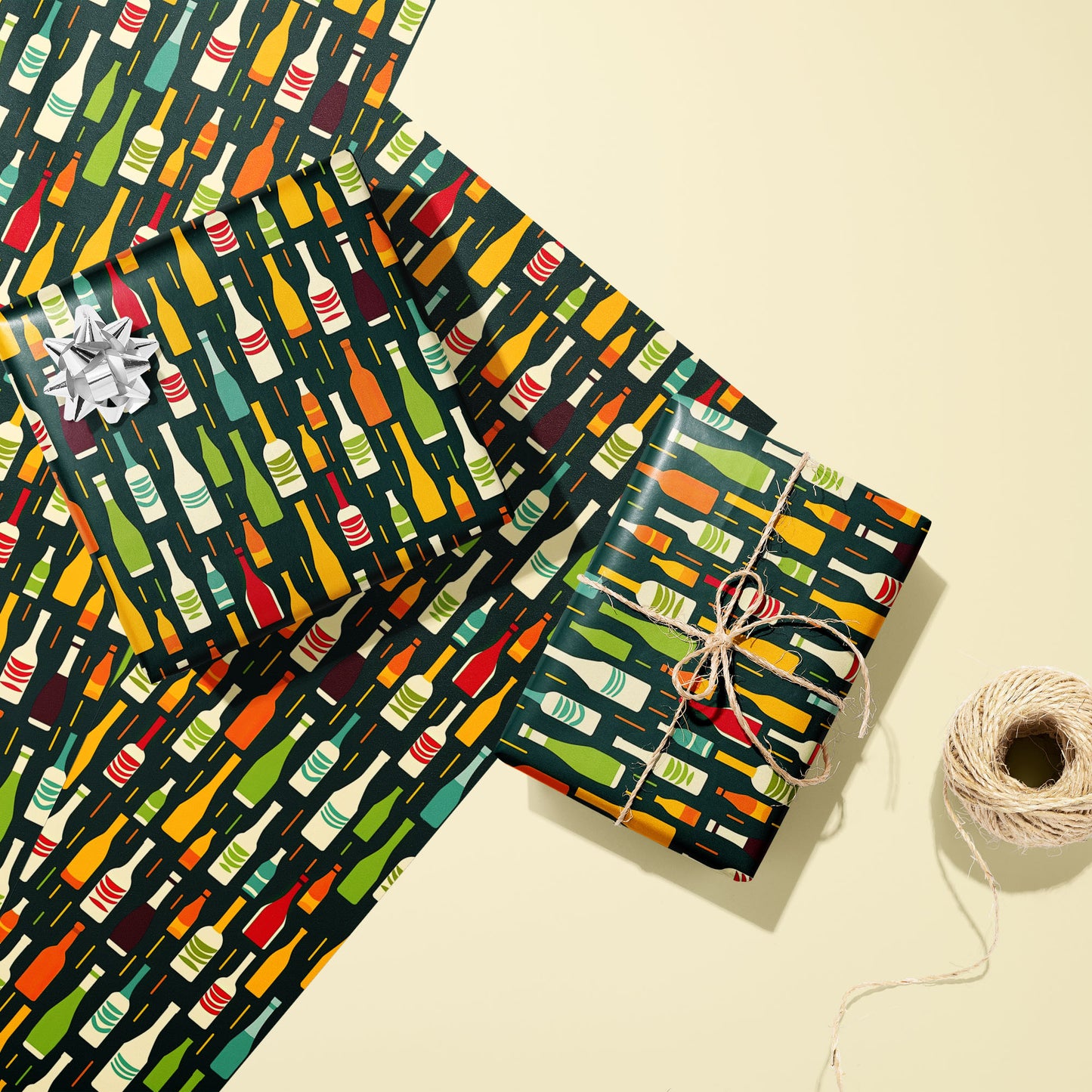 Two gifts in Wine Bottle Silhouettes—one with a silver bow and one tied with twine—rest on two unused sheets with multicolor bottle motifs on deep green beside twine on cream.