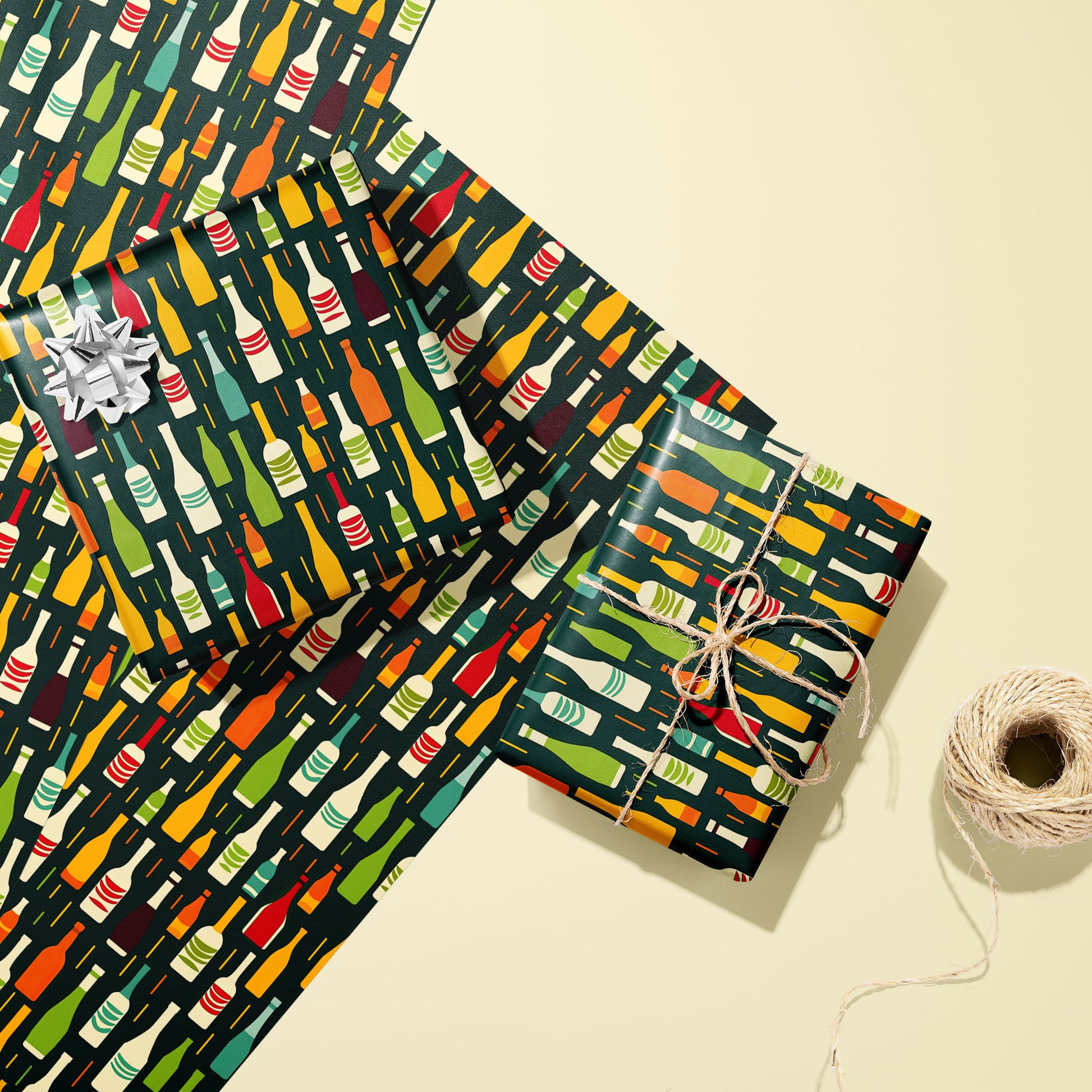Two gifts in Wine Bottle Silhouettes—one with a silver bow and one tied with twine—rest on two unused sheets with multicolor bottle motifs on deep green beside twine on cream.