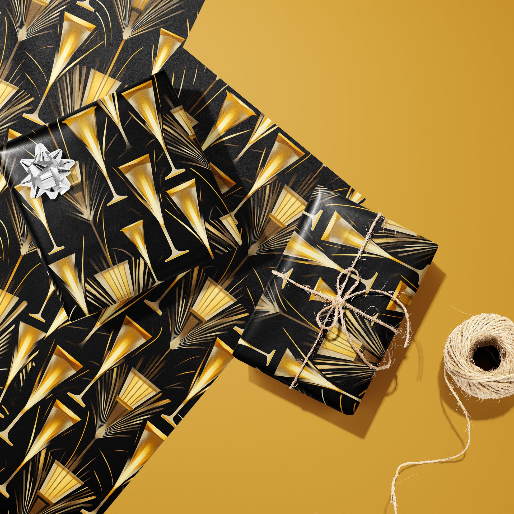 Two gifts wrapped in Flutes & Fans—one with a silver bow and one tied with twine—rest on two unused sheets beside a twine spool on a gold background with gold fans and flutes.