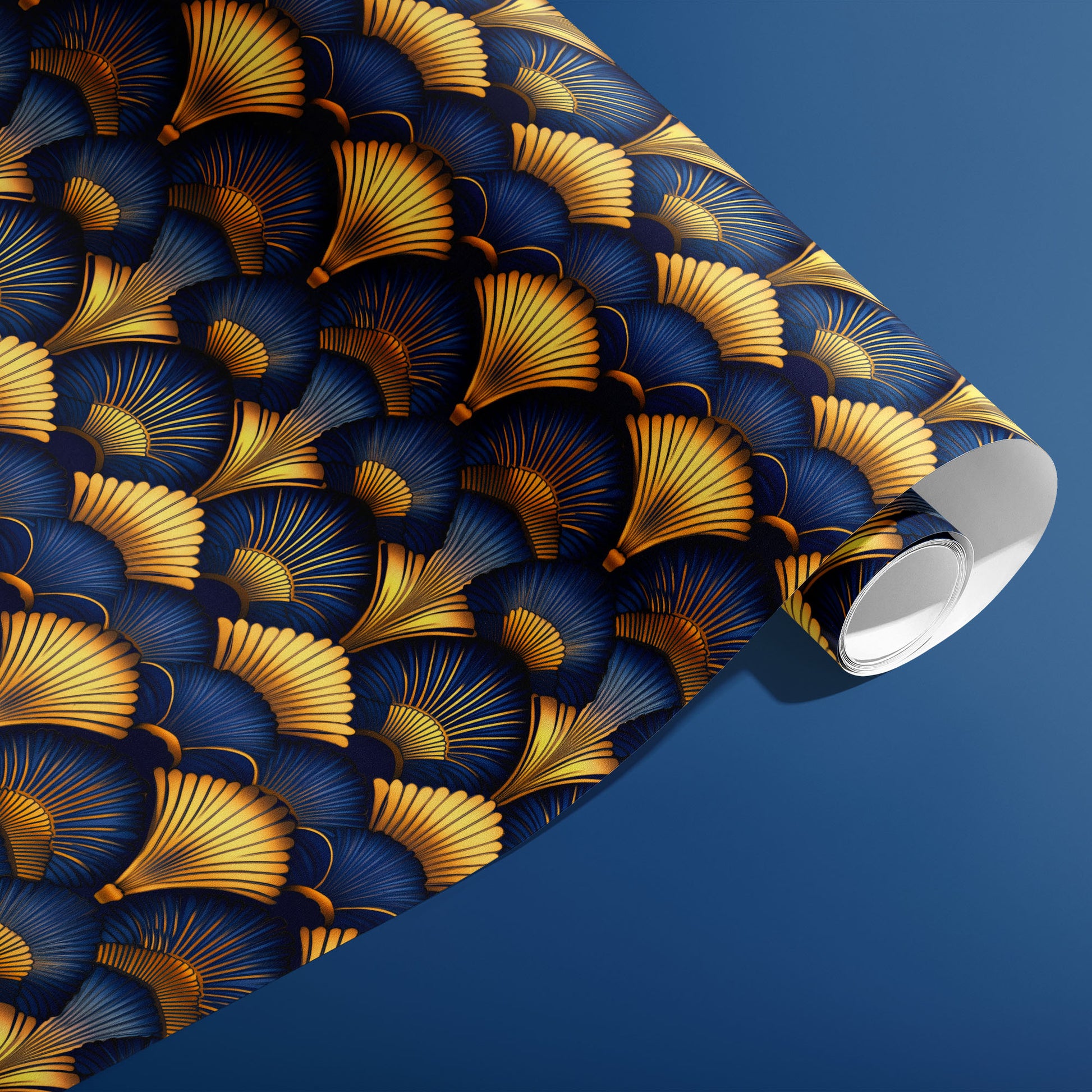 A partially unfurled roll of Gilded Ginko shows gilded fan-shaped gold and blue ginkgo leaves drifting across a dark field, resting against a blue background.