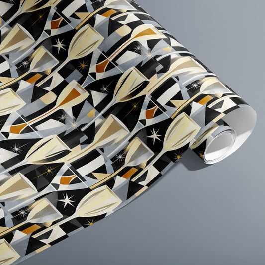 A partially unfurled roll of Toast to Elegance wrapping paper with golden champagne motifs, sparkling bubbles, and starbursts on black, resting on a silver-grey surface.