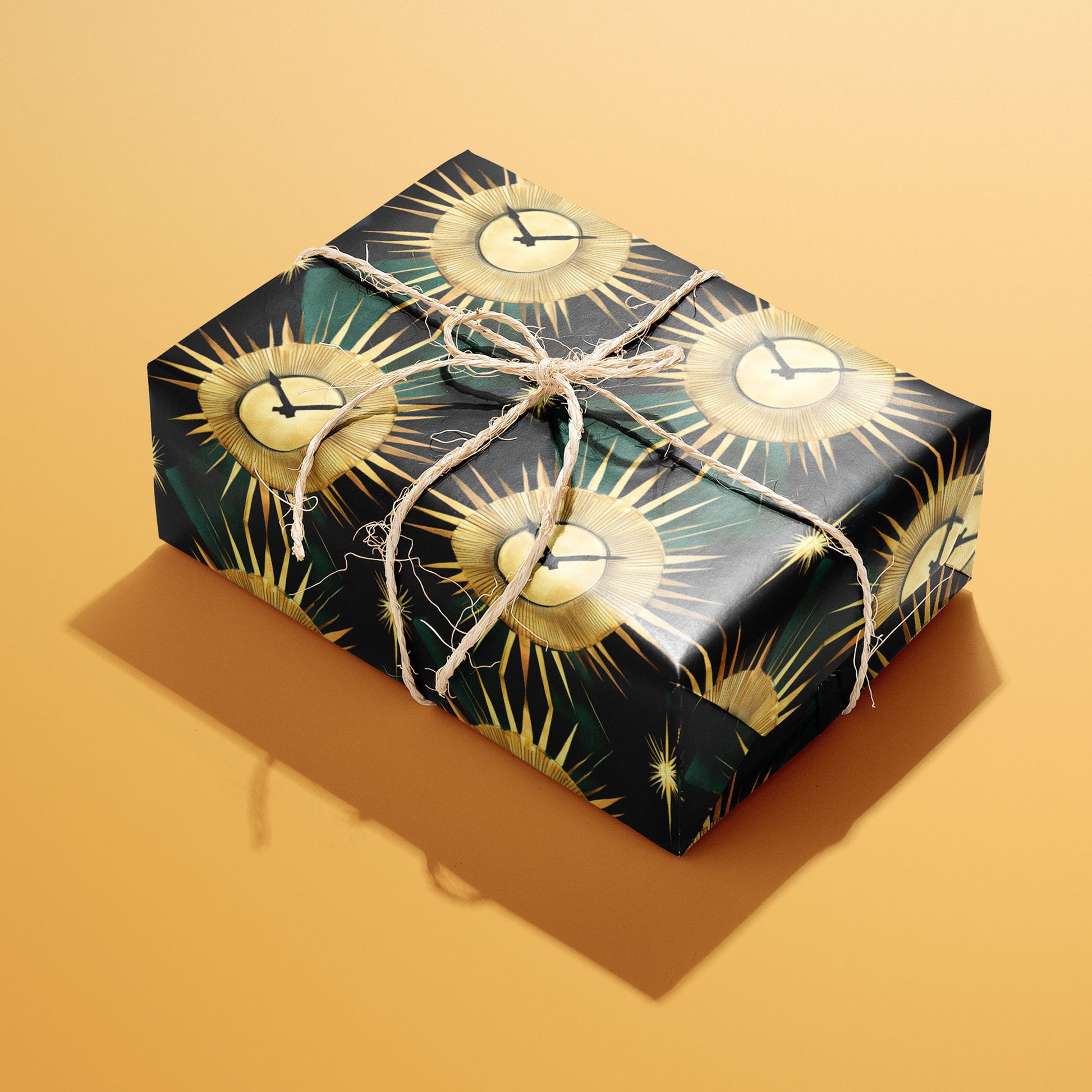 A single rectangular gift wrapped in Sunburst Clocks paper—gold sunburst clock faces on black with green accents—tied with natural twine on an ochre background.