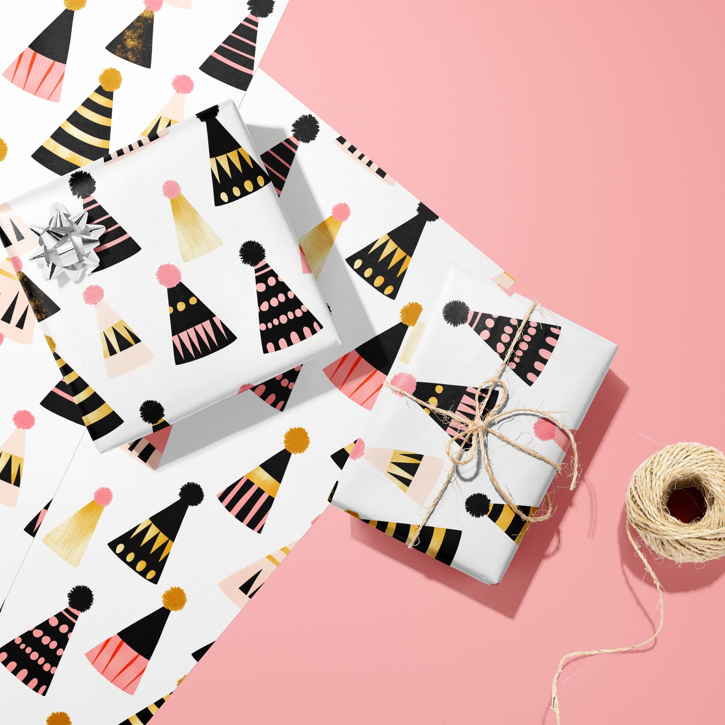 Two gifts in Party Hat Parade—one with a silver bow and one tied with twine—rest on two unused sheets beside a spool of twine on a bright pink background.