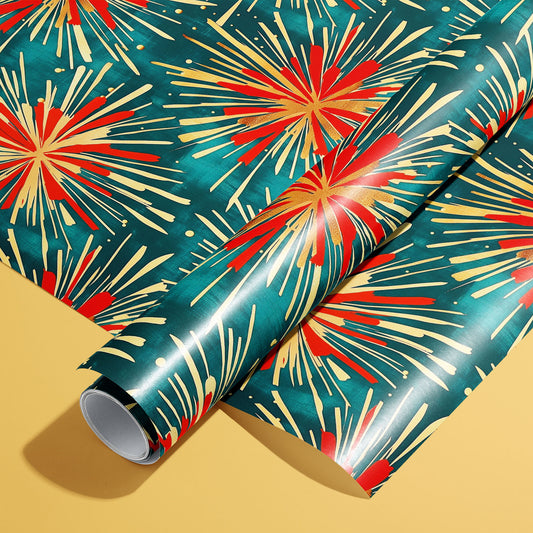 A roll of Celestial Celebration paper on a matching unrolled sheet shows red and gold fireworks bursts on deep teal, photographed on a golden yellow background.