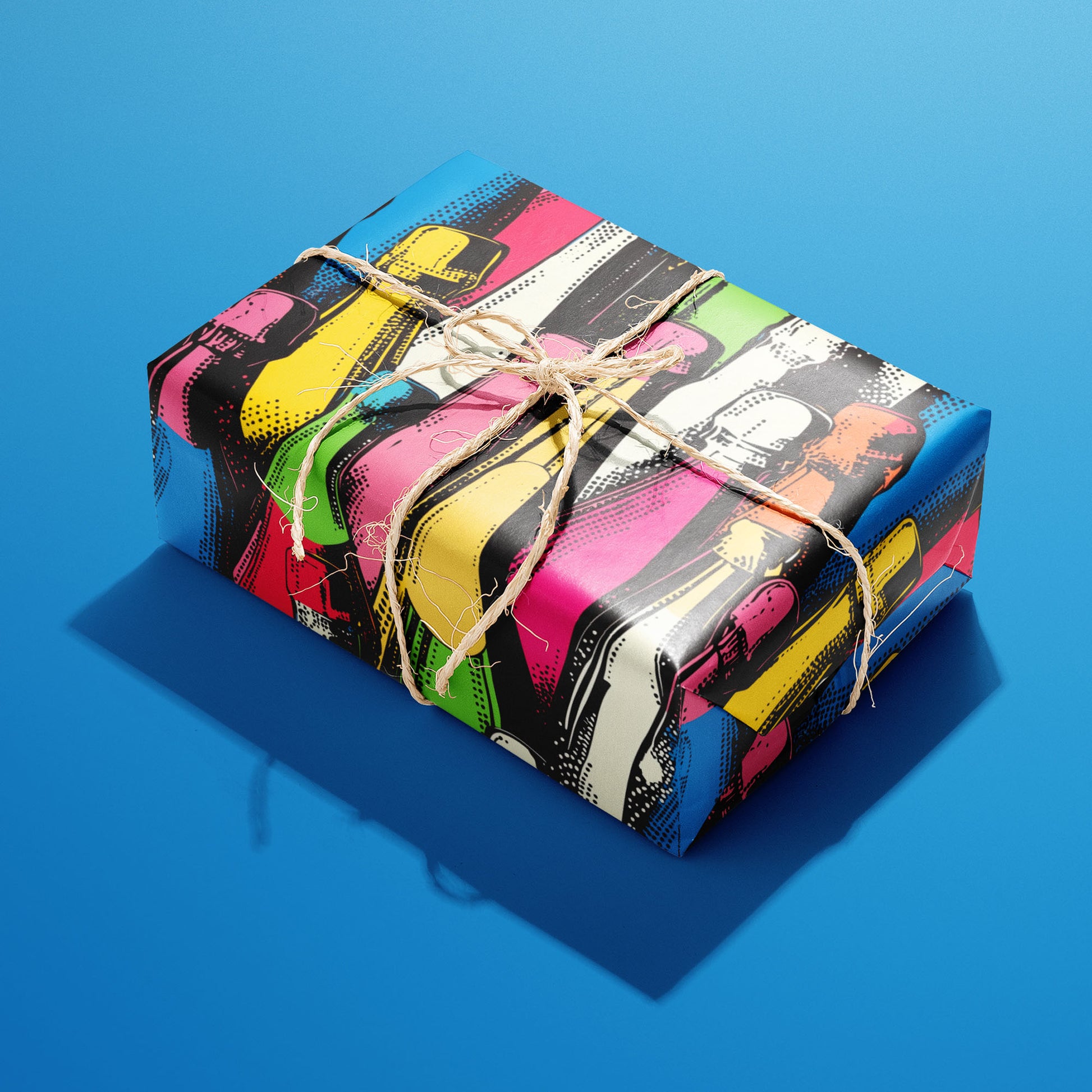A single gift wrapped in Bold Bottles and tied with natural twine displays colorful graphic bottle motifs on a deep charcoal ground against a vivid blue background.
