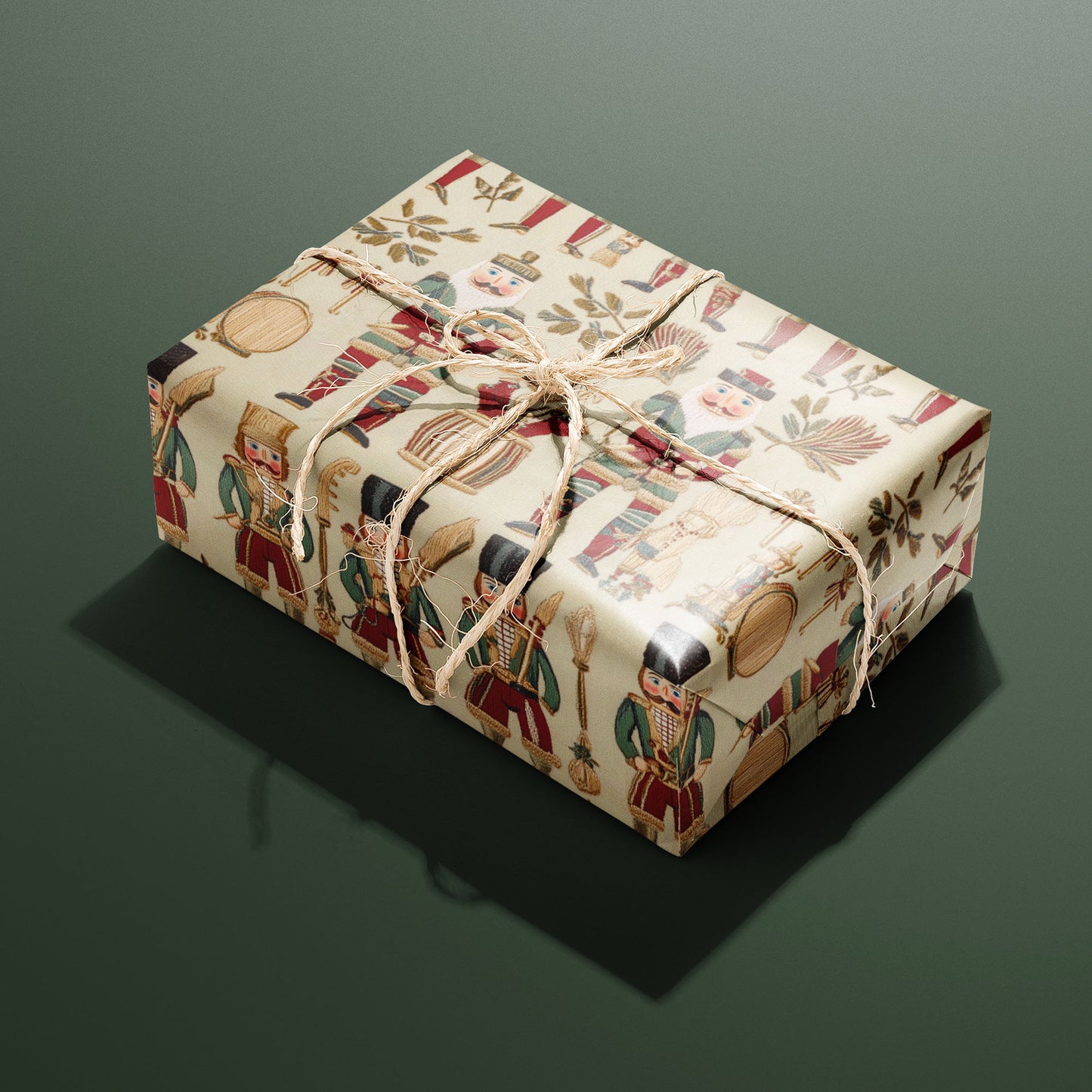 A single gift wrapped in Heritage Nutcrackers and tied with natural twine shows vintage nutcracker soldiers, drums, and foliage on a cream ground against a deep green background.