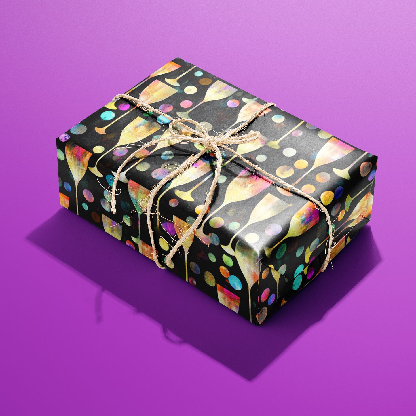 A rectangular gift wrapped in Radiant Revelry paper and tied with natural twine displays glowing champagne flutes and confetti bubbles on black against a vivid purple background.