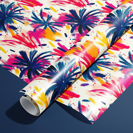 A roll of Artful Fireworks paper on a matching unrolled sheet shows painterly firework bursts with lively brushstrokes and splashes in magenta, cobalt, and gold on cream, resting on a navy blue surface.