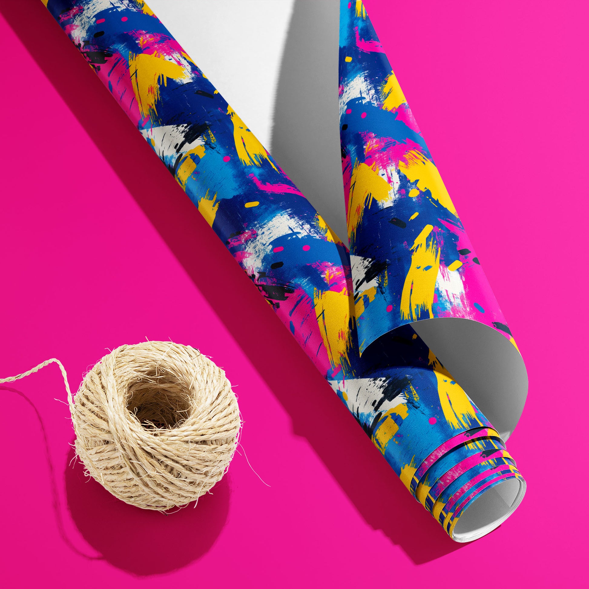 A partially unfurled Electric Splash roll with the white underside beside natural twine shows neon brushstrokes with black dashes and white splatters on a hot pink background.