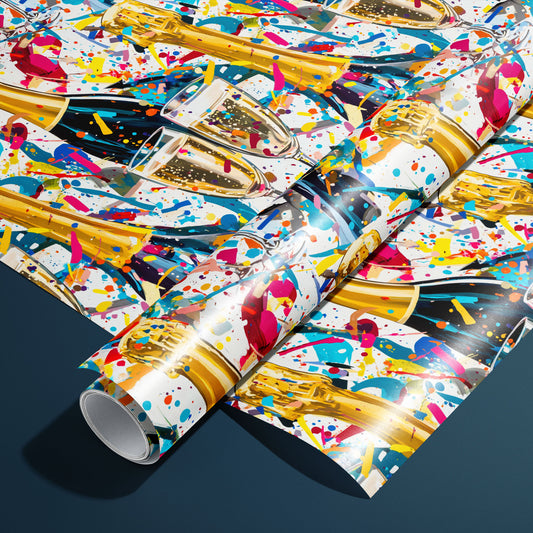 A roll of Glitter & Fizz paper on a matching unrolled sheet shows black and gold champagne bottles, fizzy bubbling flutes, and sparkling confetti on white, resting on a charcoal gray background.