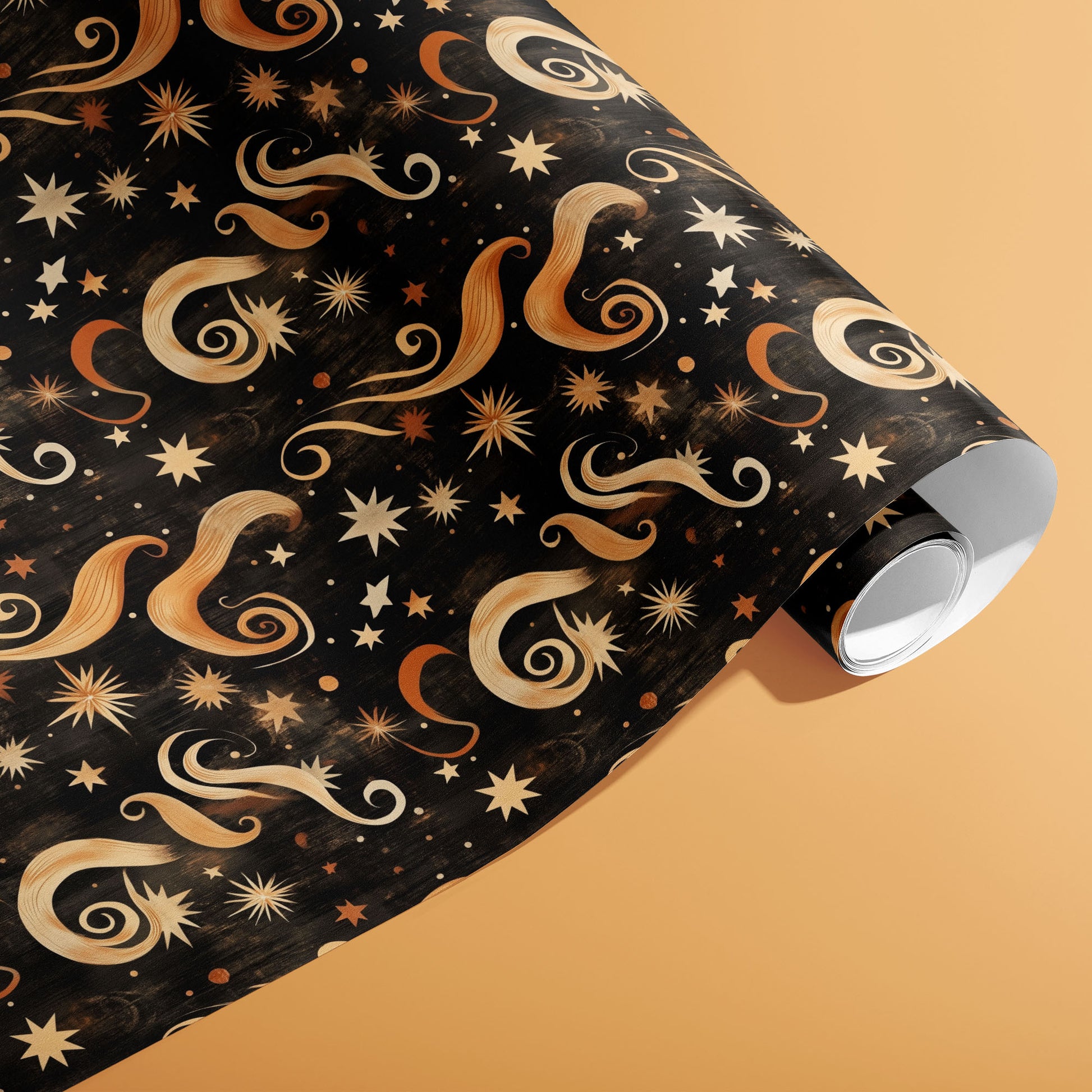 A partially unfurled roll of Golden Stardust wrapping paper featuring gold stars and sweeping celestial swirls on a warm peach background.