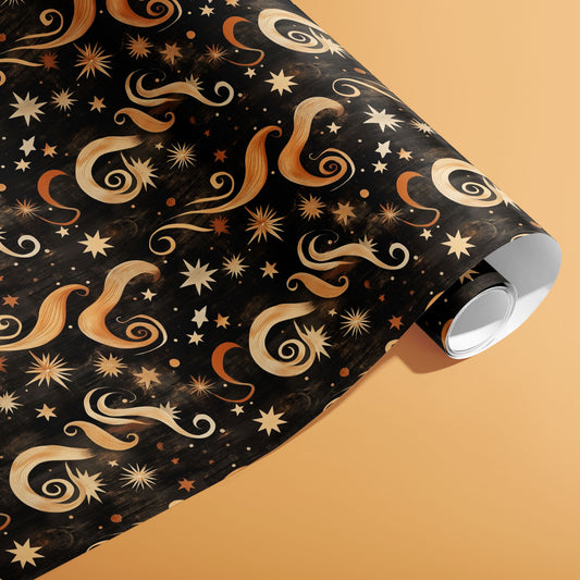 A partially unfurled roll of Golden Stardust wrapping paper featuring gold stars and sweeping celestial swirls on a warm peach background.