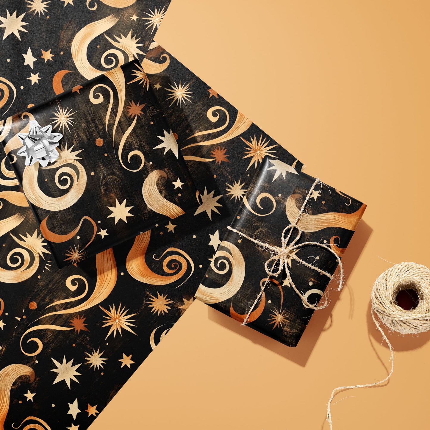 Two gifts wrapped in Golden Stardust—one with a silver bow, one tied with twine—rest on two matching sheets beside a twine spool on a warm peach background.