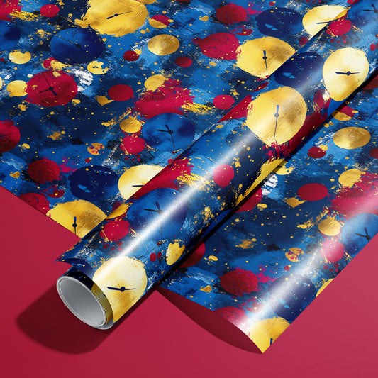 A roll on an unrolled sheet of Time to Shine wrapping paper with painterly clock-face baubles in gold, red, and blue with splatters, set on a bold cranberry-red background.