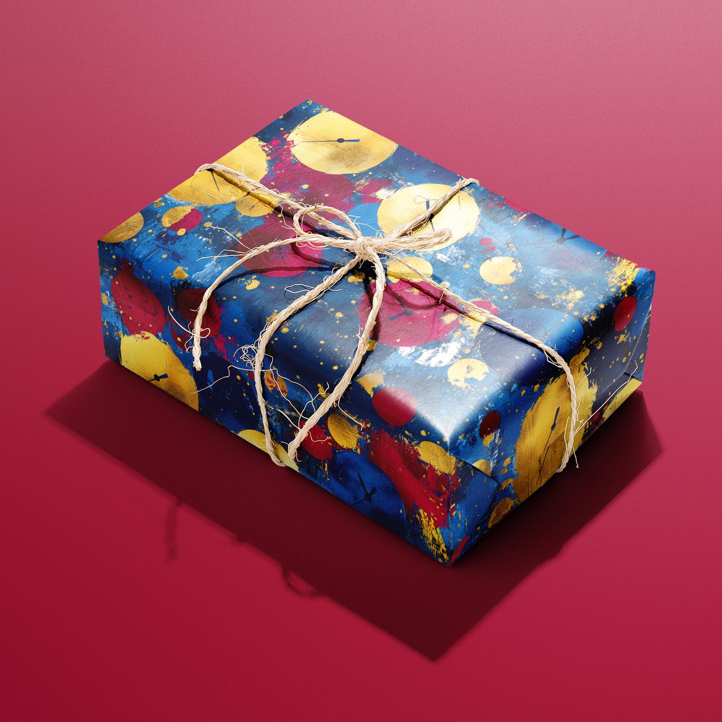 A single rectangular gift wrapped in Time to Shine paper—painterly gold, red, and blue clock baubles—tied with natural twine on a cranberry-red background.