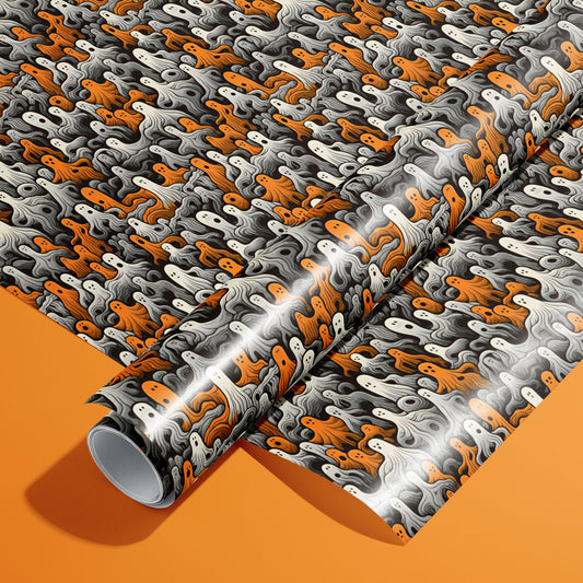 A roll of Cute Ghosts wrappingh paper rests on a matching unrolled sheet, covered in orange, white, and gray cartoon ghosts with wavy swirls on charcoal black, photographed on an orange background.
