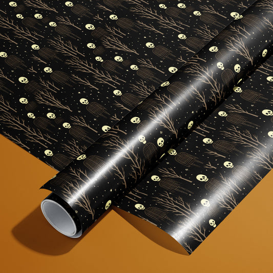A roll of Skeletons paper on a matching unrolled sheet shows pale skulls and ribcage figures among leafless trees and speckles on deep black, photographed on a warm ochre background.