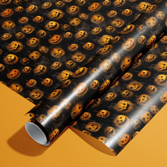 A roll of Jack-o-Lanterns paper on a matching unrolled sheet shows glowing carved pumpkins on a smoky black ground, perfect for Halloween, set on an orange background.