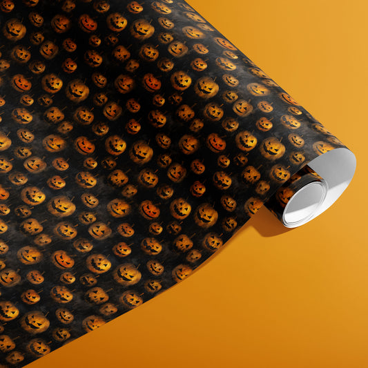 A partially unfurled roll of Jack-o-Lanterns wrapping paper reveals glowing carved pumpkins across a smoky black pattern, photographed on an orange background.