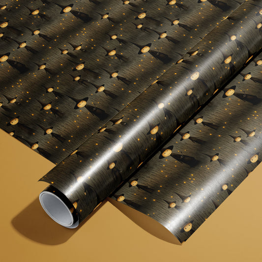 A roll on an unrolled sheet of Halloween Witches wrapping paper with cloaked witches in pointy hats amid amber sparks on a charcoal woodgrain, set on a warm mustard background.