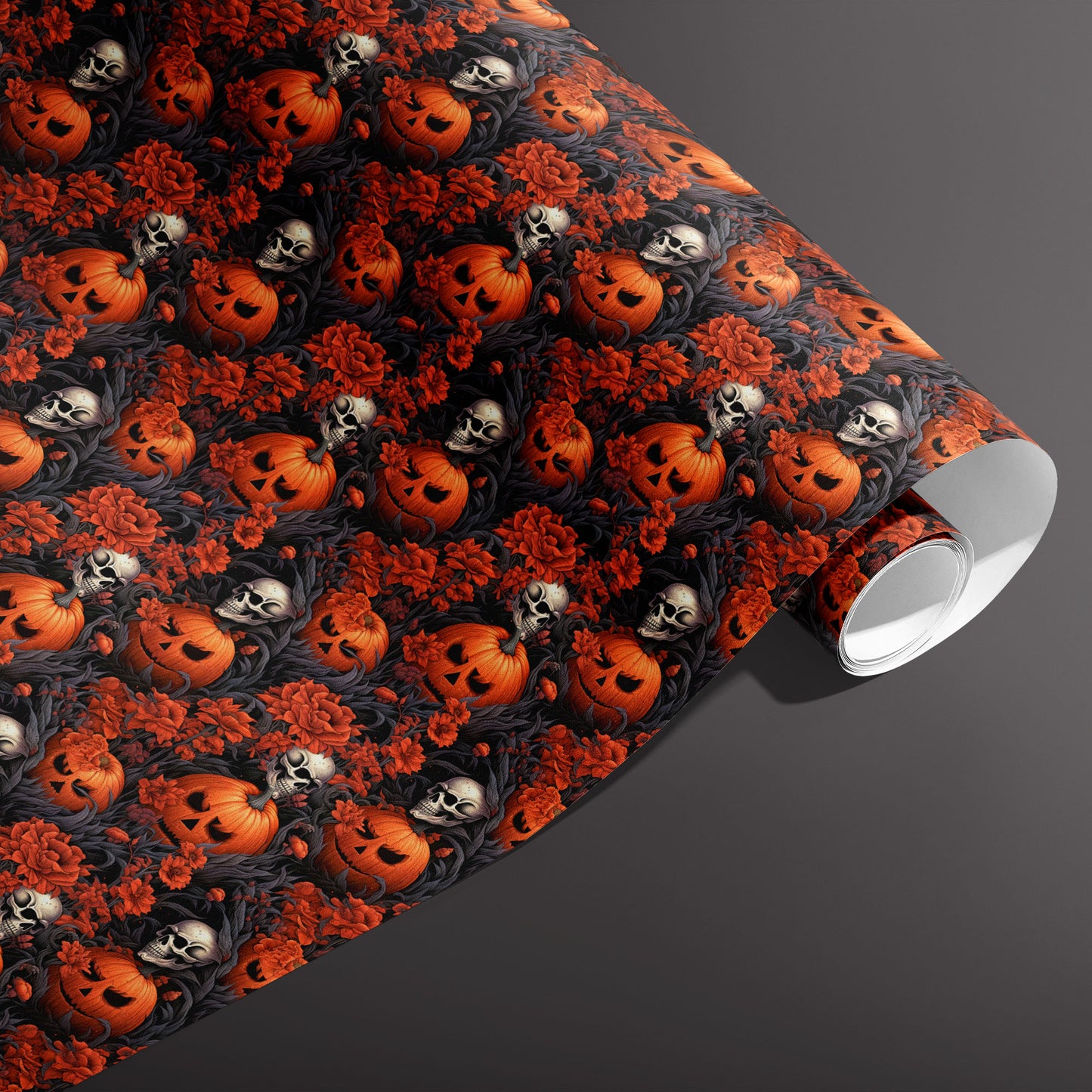 A partially unfurled roll of Ghastly Grove paper featuring Halloween pumpkins, skulls, and crimson flowers in gothic foliage on black, set against a dark gray background.