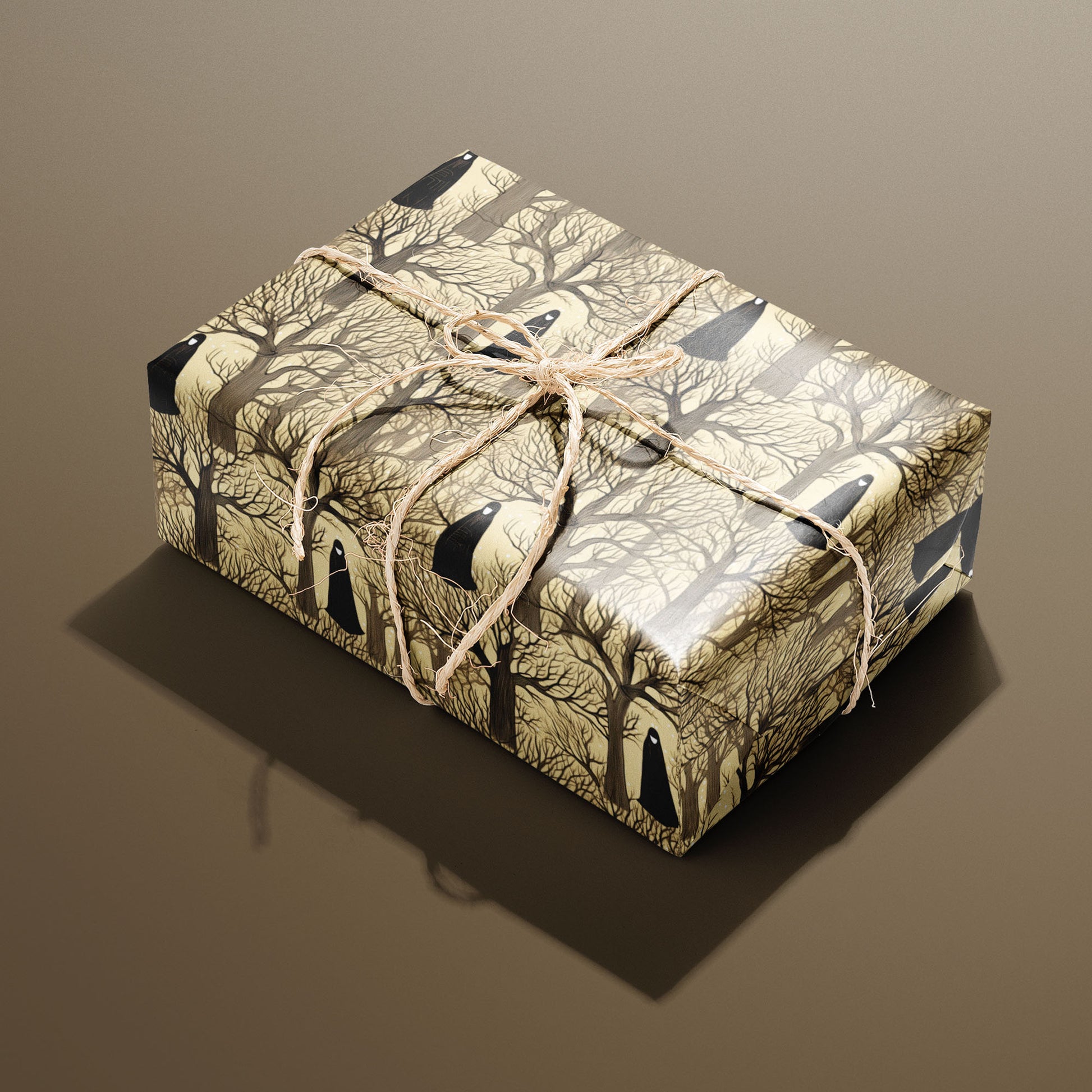 A single rectangular gift wrapped in Silent Forest and tied with natural twine highlights cloaked figures and winter trees on a parchment-tan ground against a warm brown backdrop.