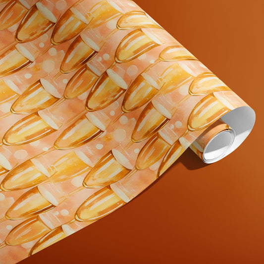 A partially unfurled roll of Shimmering Sips wrapping paper showing golden champagne flutes and bubbly dots on a peachy ground against a copper-orange background.