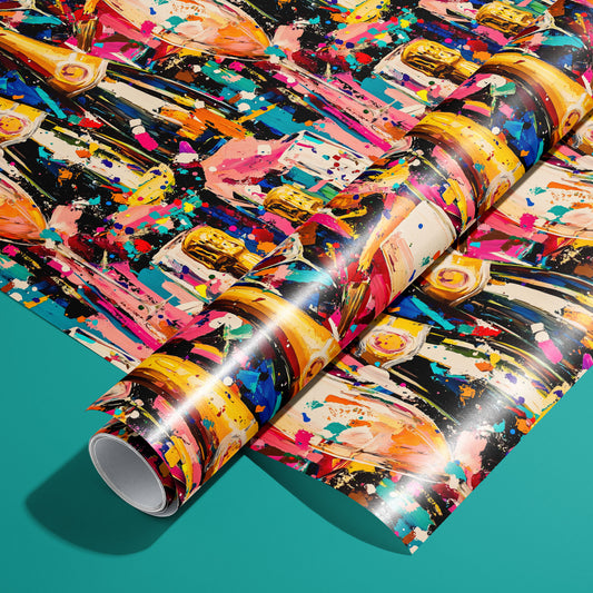 A roll of Cheers in Color wrapping paper on an unrolled sheet, featuring champagne bottles, flutes, and paint-splatter confetti on a dark ground, set on a teal background.