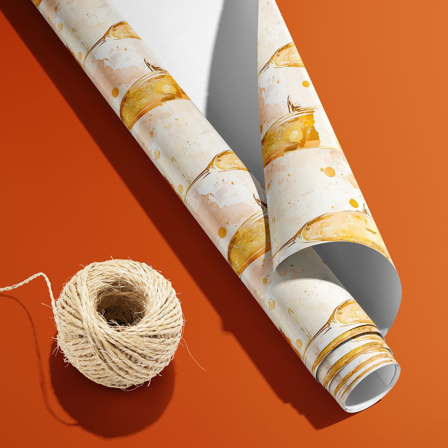 A partially unfurled roll of Sparkling Celebrations with the white underside visible sits beside natural twine on an orange surface, revealing bubbly flutes on blush cream.