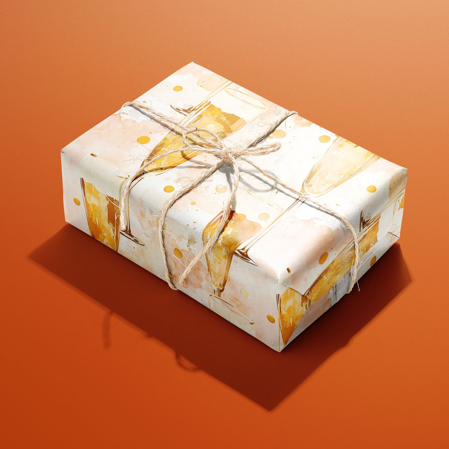 A single gift wrapped in Sparkling Celebrations and tied with natural twine shows watercolor champagne flutes and bubbly dots on a blush cream ground against an orange background.