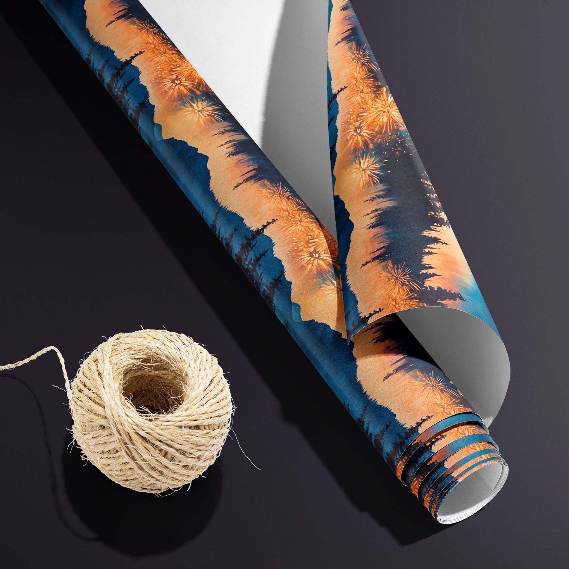 A partially unfurled roll of Radiant Reflections with the white underside visible sits beside natural twine on a charcoal-purple surface, revealing fireworks, pines, and water reflections.