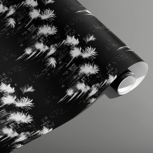 A partially unfurled roll of Fireworks Fantasy black-and-white wrapping paper showing neon burst patterns and glittering starlets on a deep black ground against a slate gray background.