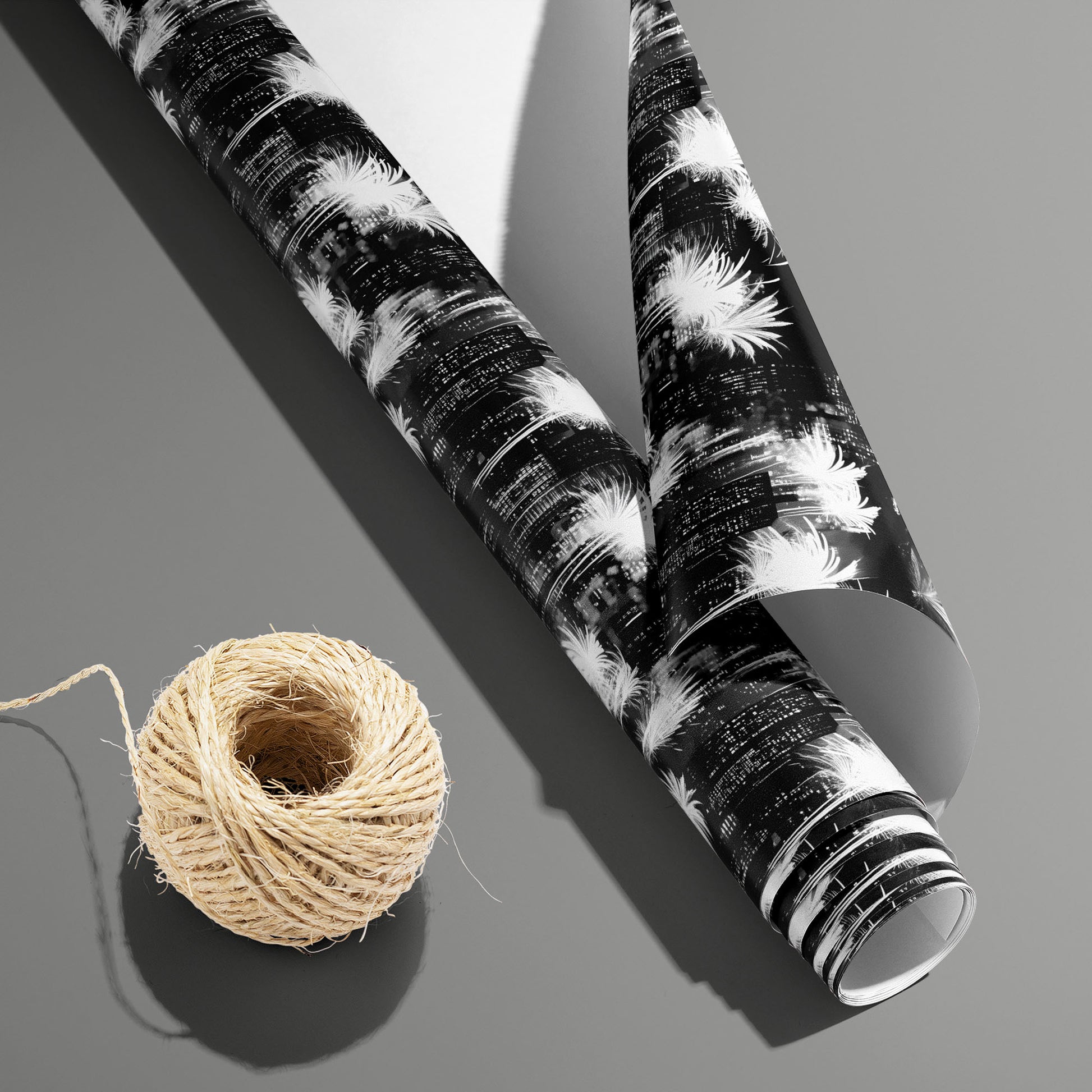A partially unfurled Fireworks Fantasy roll with the white underside visible beside a spool of natural twine, featuring fireworks on a slate gray surface.