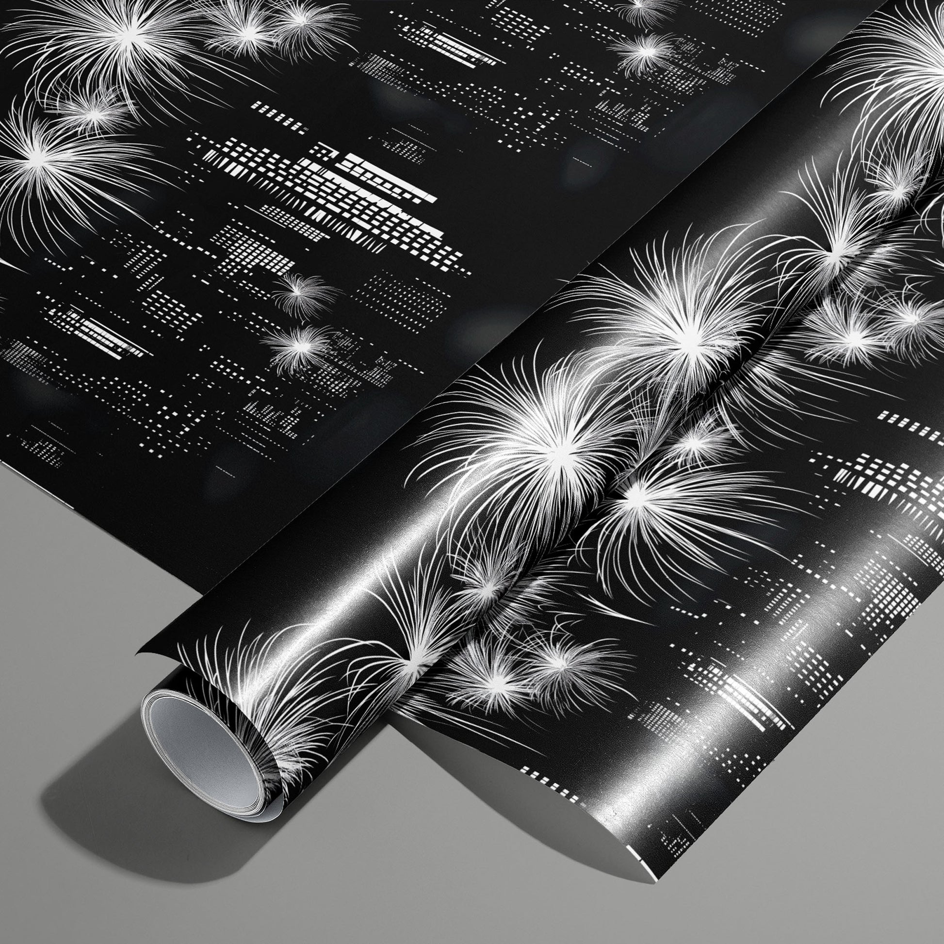 A roll of Skyline Magic wrapping paper on an unrolled sheet, showing a black-and-white city skyline with fireworks and geometric building lights, on a medium gray surface.