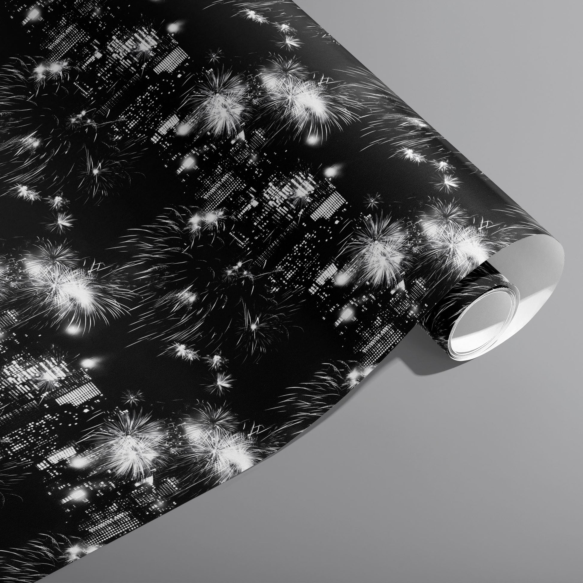 A partially unfurled roll of Skyline Celebration wrapping paper featuring glowing city lights and white fireworks over a black ground on a cool gray background.