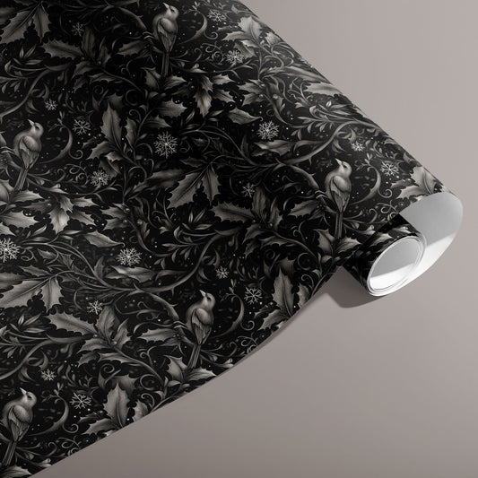 A partially unfurled roll of Winter Song wrapping paper shows silver-gray birds, holly, and swirling vines with snowflakes on a black ground against a taupe backdrop.