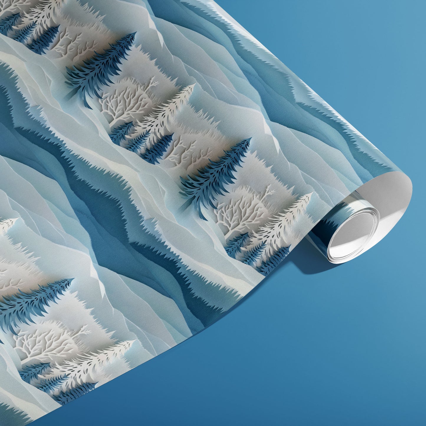 A partially unfurled roll of Snowy Grove wrapping paper showing stylized snowy evergreens and bare branches in tonal blues on a medium blue background.