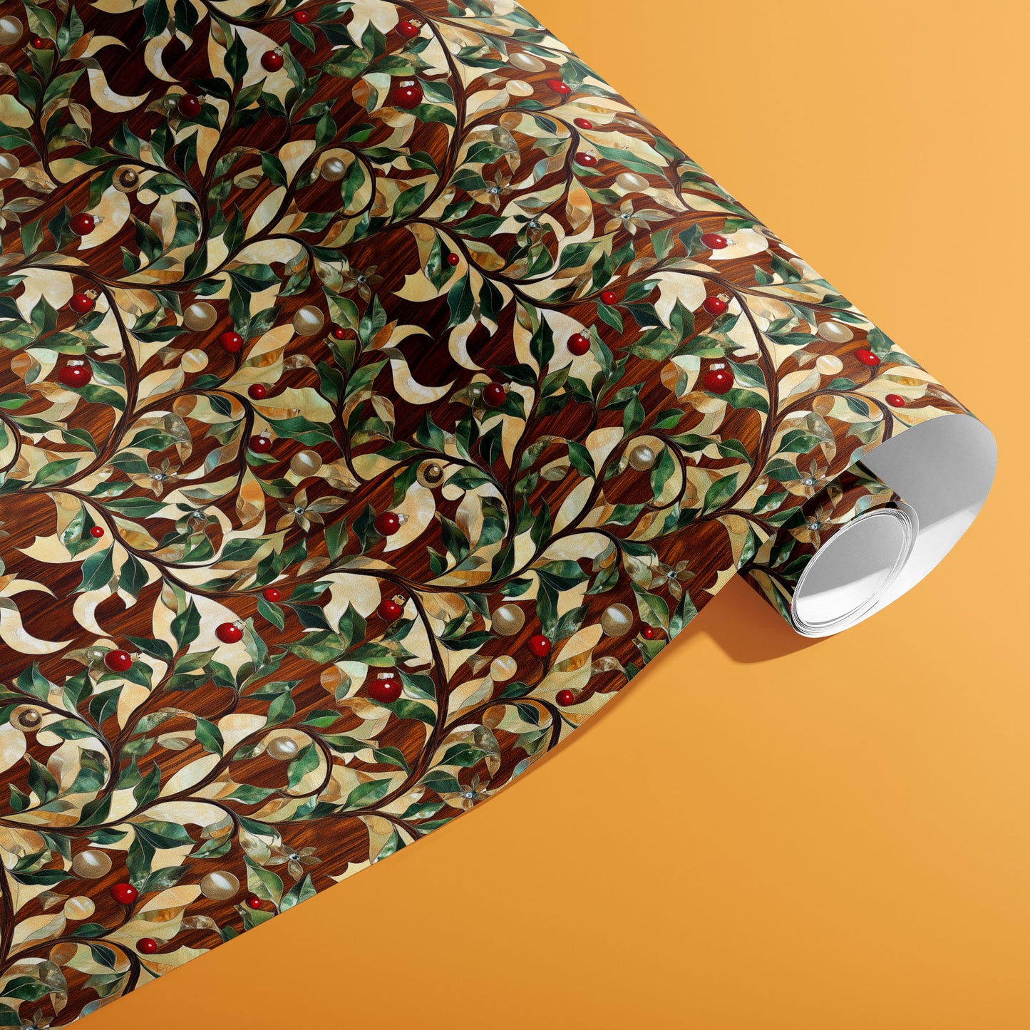 A partially unfurled roll of Gilded Greenery wrapping paper showing gold-touched vines, lush leaves, and red berries on a woodgrain pattern atop a warm orange background.