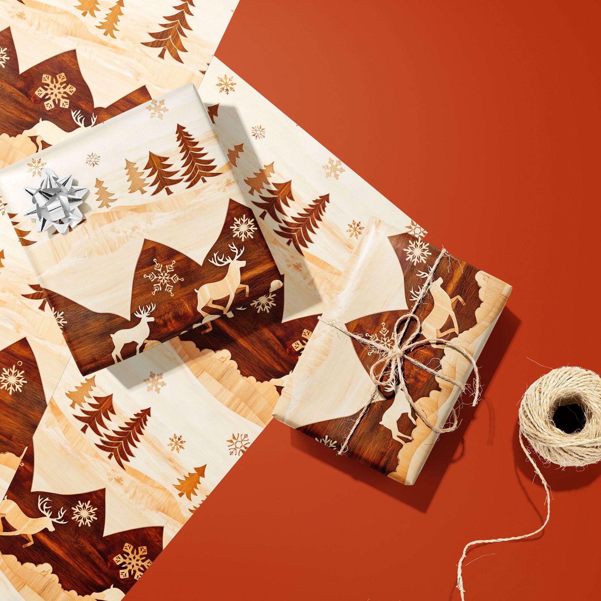 Two gifts in Rustic Reindeer—one silver-bowed and one tied with twine—rest on two unused sheets with woodgrain reindeer and trees on cream beside twine on burnt orange.