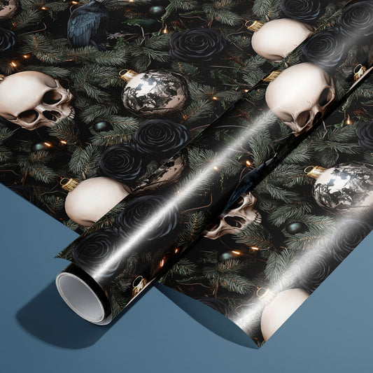 A roll of Dark Yuletide rests on a matching unrolled sheet, featuring skull ornaments, ravens, black roses, evergreen boughs, and warm fairy lights on a black ground over a steel blue surface.