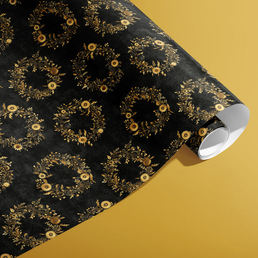 A partially unfurled roll of Clockwork Wreaths paper showing gold mechanical cog wreaths and leafy flourishes across a textured black ground on a mustard-yellow background.