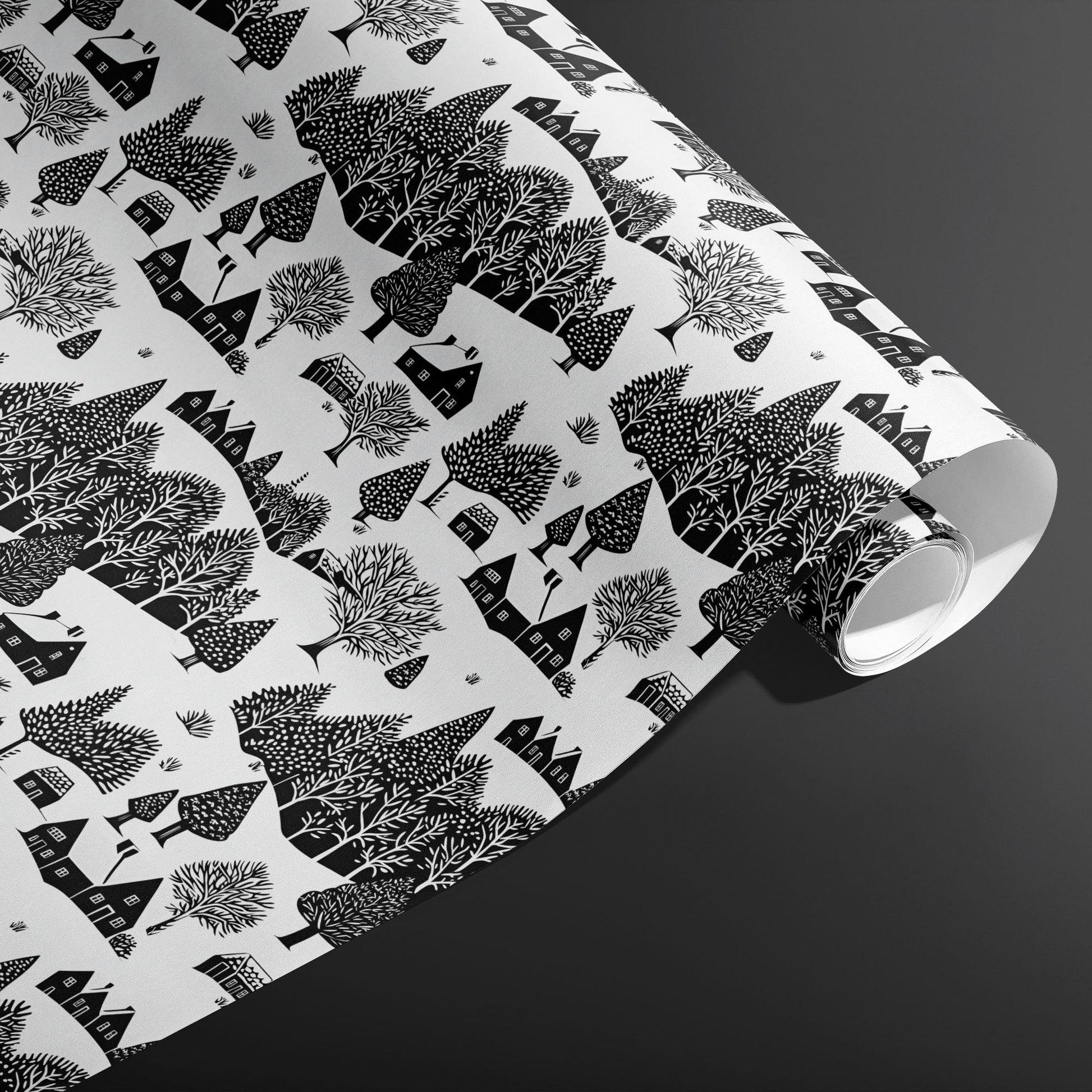 A partially unfurled roll of Snowbound Village showing cozy cottages and snow-dotted trees in black on white against a dark gray backdrop.