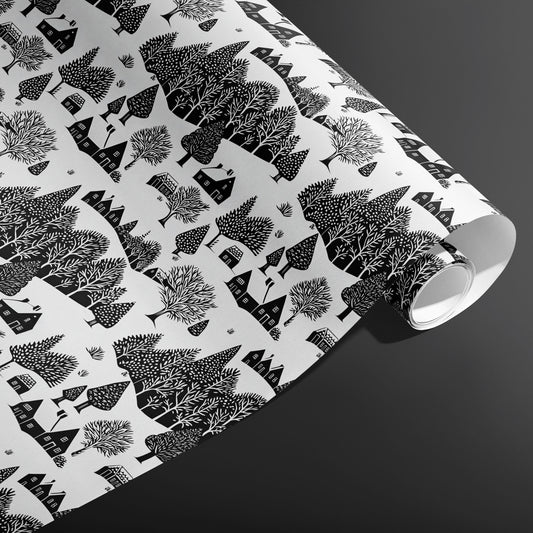 A partially unfurled roll of Snowbound Village showing cozy cottages and snow-dotted trees in black on white against a dark gray backdrop.