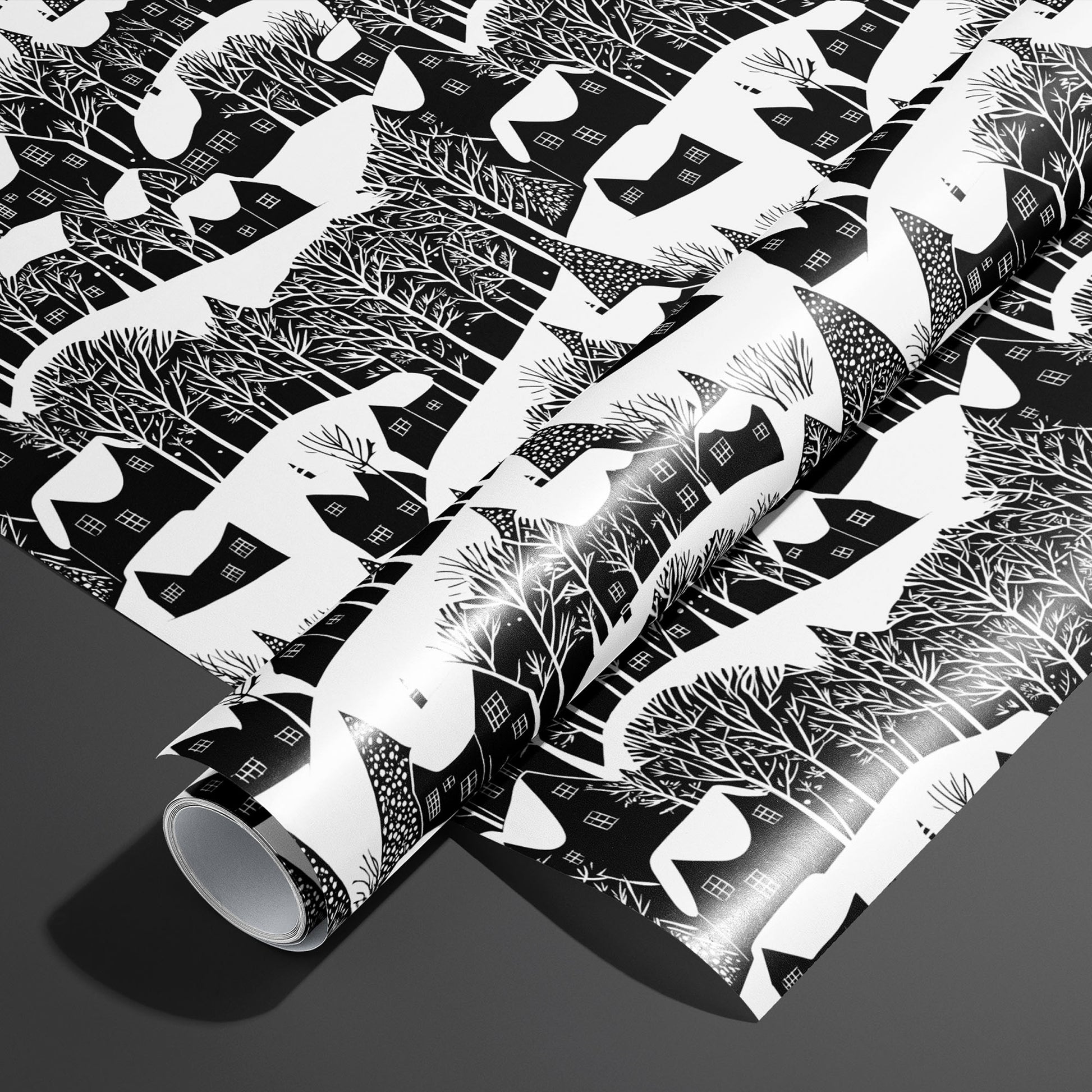 A roll of Snowy Silhouette rests on an unrolled sheet, showing black-and-white village silhouettes with snowy roofs and bare trees, styled on a charcoal gray surface.