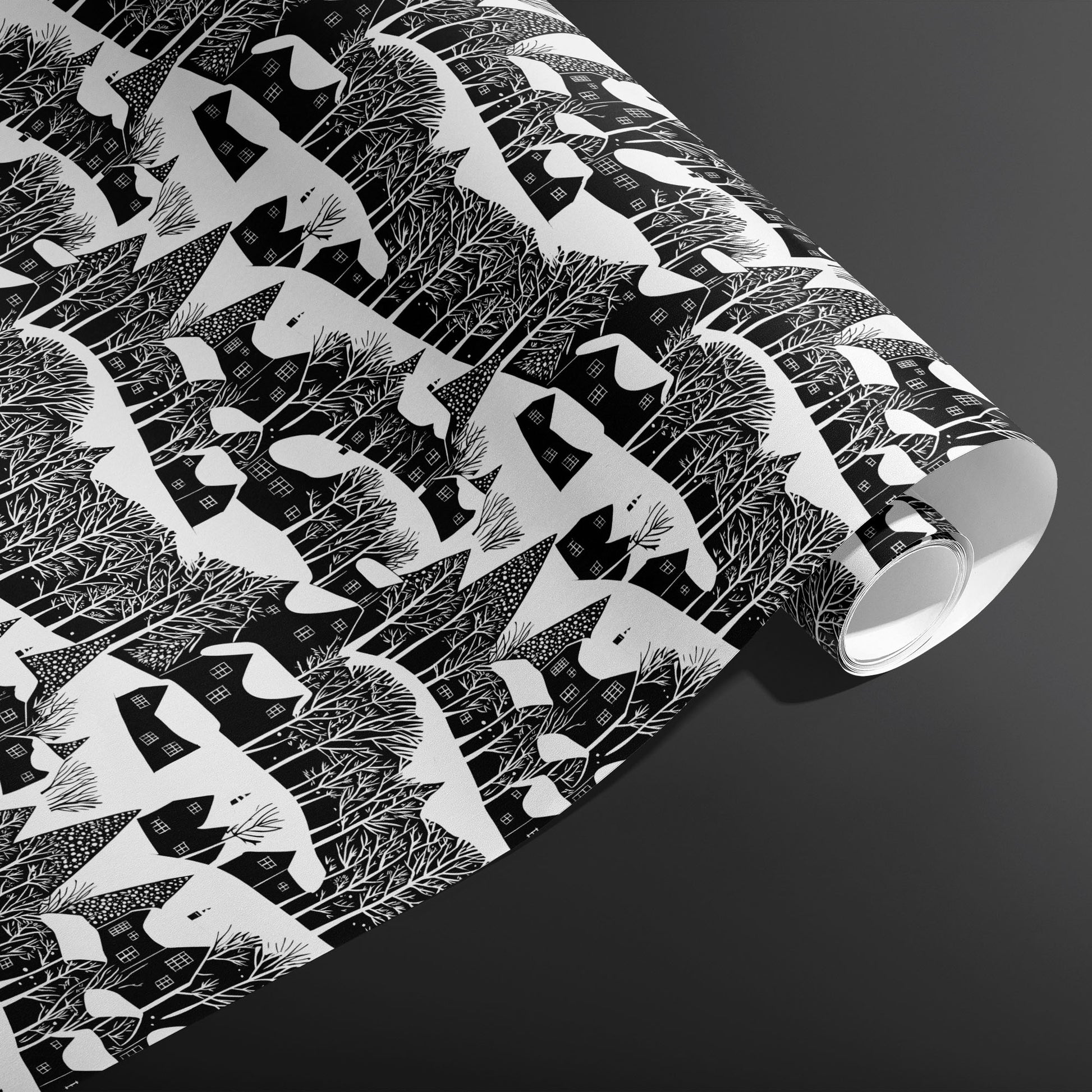 A partially unfurled roll of Snowy Silhouette displays snowy cottage and forest silhouettes in crisp black and white against a charcoal gray background.