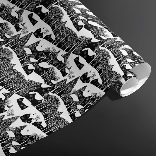 A partially unfurled roll of Snowy Silhouette displays snowy cottage and forest silhouettes in crisp black and white against a charcoal gray background.
