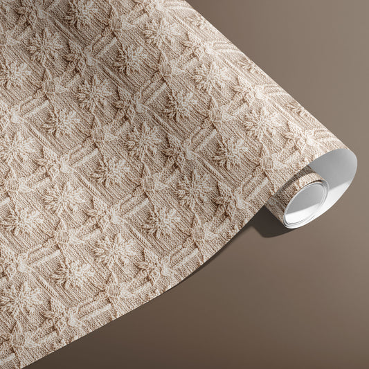 A partially unfurled roll of Winter Weave gift wrap displays a textured knit snowflake motif in soft cream and beige against a warm brown background.