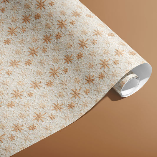 A partially unfurled roll of Hygge Holiday paper showing cozy knit snowflake motifs in tan on white against a caramel-brown backdrop.