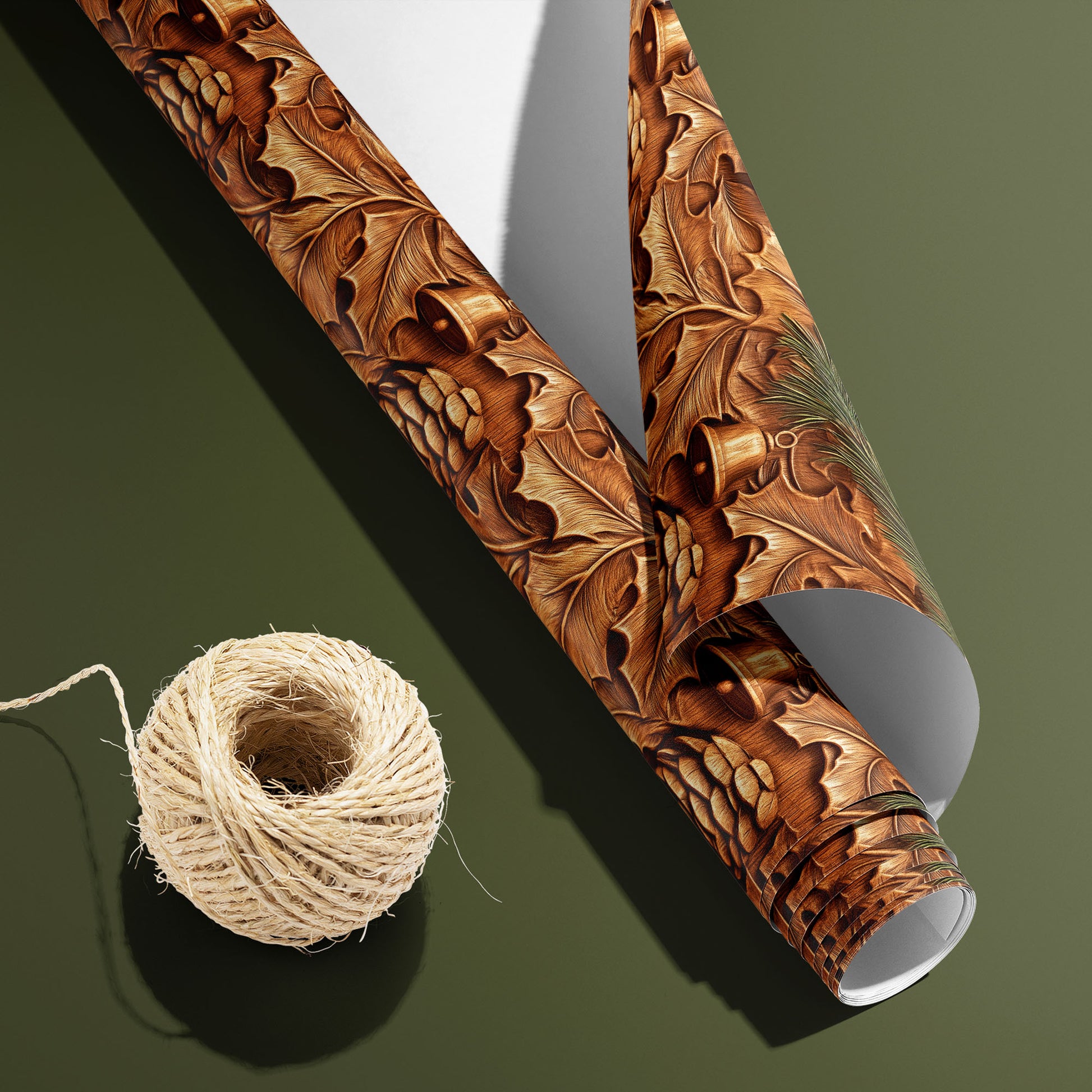 A partially unfurled roll of Pinewood Bells, white underside visible beside a spool of natural twine, shows carved-wood bells and pinecones on an olive green surface.