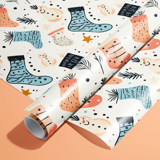 A roll on an unrolled sheet of Snowy Stockings wrapping paper with playful snowmen, knit stockings, pine sprigs, and confetti dots on a warm peach background.